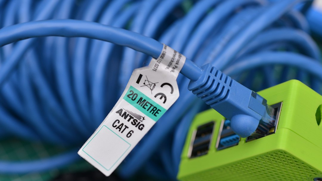 Residential Services A detailed close-up shot of a blue Cat 6 Ethernet cable plugged into a vibrant green device. The image features a shallow depth of field, emphasizing the cables texture and the crispness of the connector. The contrasting blue and green colors create a visually striking composition, perfect for tech-related projects or website backgrounds.